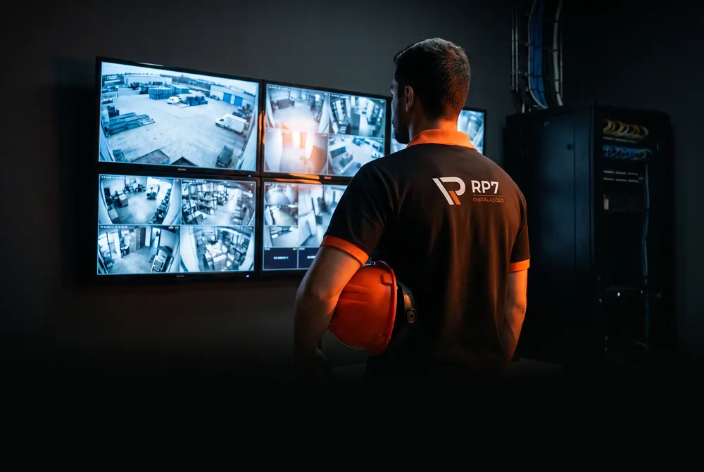 Central de monitoramento com técnico da RP7 diante dos monitores de CFTV